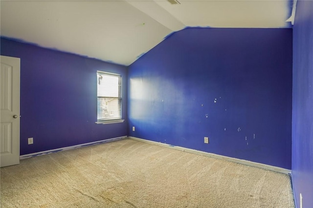 carpeted empty room featuring lofted ceiling and baseboards