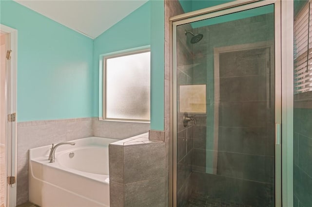 bathroom with a stall shower, a garden tub, and vaulted ceiling