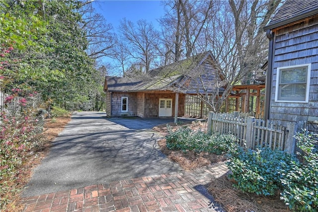 view of home's exterior featuring fence, aphalt driveway, and french doors