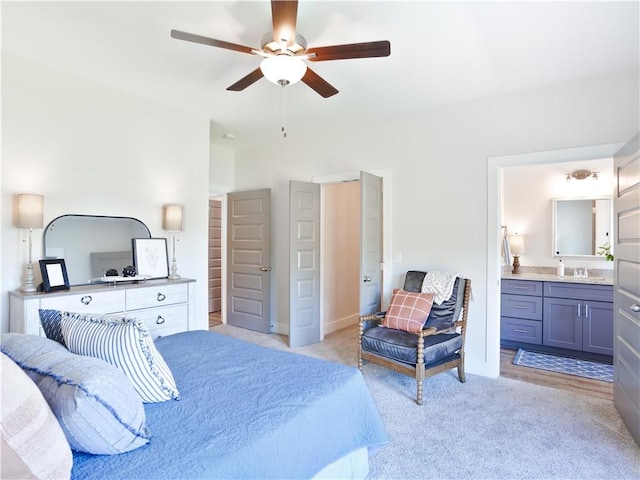 bedroom with baseboards, light colored carpet, ensuite bathroom, a ceiling fan, and a sink