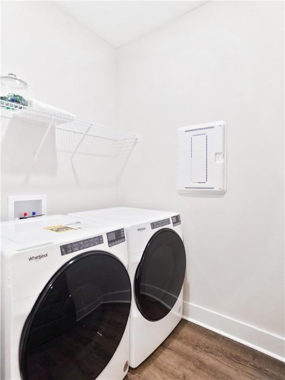 clothes washing area featuring independent washer and dryer, laundry area, wood finished floors, and baseboards