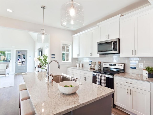 kitchen featuring a sink, decorative backsplash, appliances with stainless steel finishes, and white cabinetry