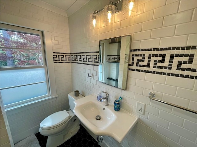 bathroom featuring toilet, tile walls, and a sink