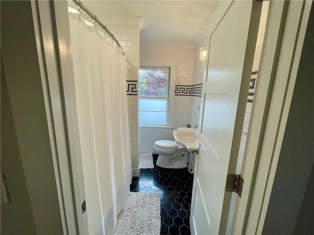 bathroom featuring toilet, ornamental molding, tile walls, and tile patterned floors