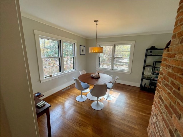 dining room featuring a wealth of natural light, wood finished floors, visible vents, and crown molding