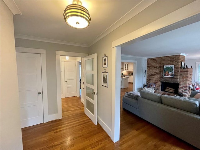 corridor featuring baseboards, wood finished floors, and crown molding