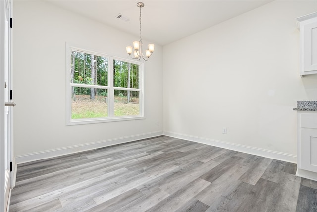 unfurnished dining area with light wood-type flooring and an inviting chandelier