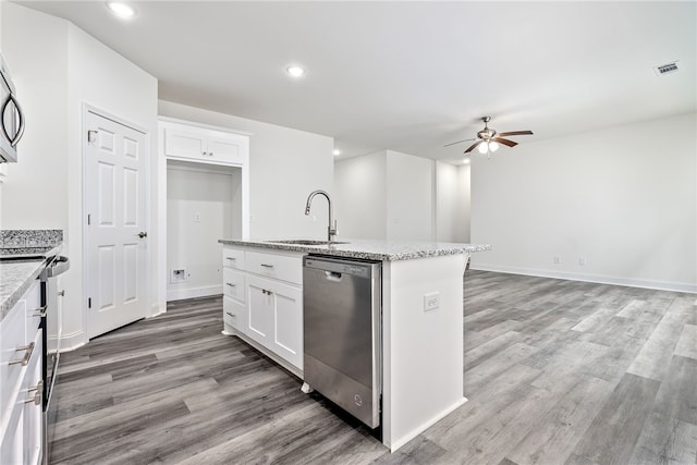 kitchen with light stone countertops, stainless steel appliances, sink, white cabinetry, and an island with sink