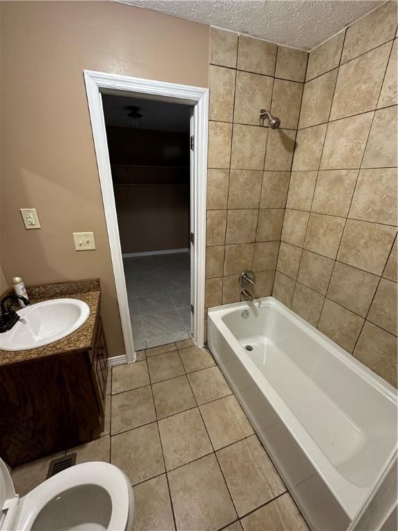 full bathroom featuring tile patterned flooring, vanity, toilet, and a textured ceiling