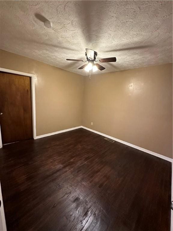 unfurnished room with ceiling fan, dark hardwood / wood-style flooring, and a textured ceiling