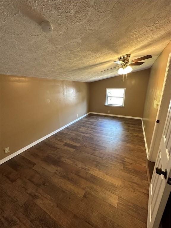 empty room with a textured ceiling, ceiling fan, dark hardwood / wood-style flooring, and lofted ceiling