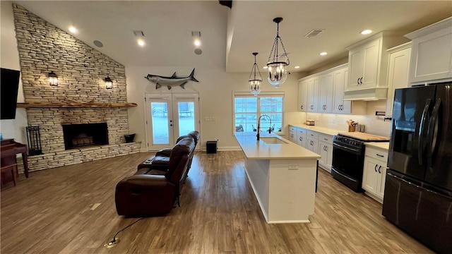 kitchen with white cabinetry, sink, black appliances, and an island with sink