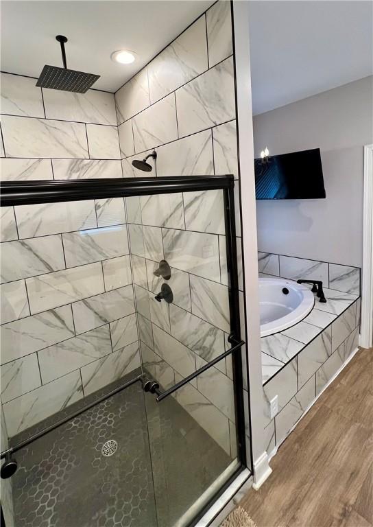 bathroom with hardwood / wood-style flooring and shower with separate bathtub