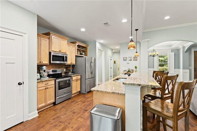 4112 Creekview Ct, Auburn, AL 36832 - kitchen featuring stainless steel appliances, light brown cabinetry, arched walkways, a kitchen bar, and wood finished floors