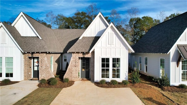 modern farmhouse style home with board and batten siding, brick siding, and roof with shingles