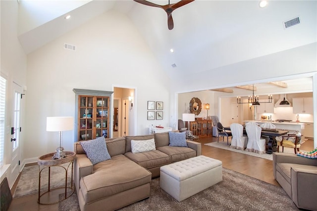 living room with high vaulted ceiling and ceiling fan with notable chandelier