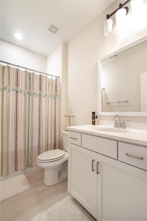 bathroom featuring a shower with curtain, toilet, vanity, and hardwood / wood-style flooring