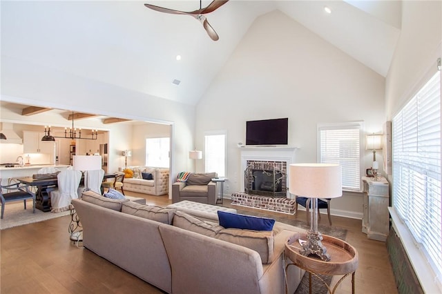 living room with hardwood / wood-style floors, ceiling fan with notable chandelier, plenty of natural light, and a fireplace