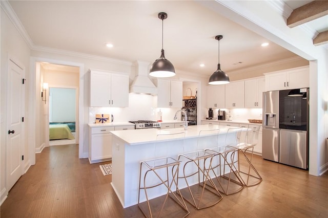 kitchen featuring stainless steel appliances, beamed ceiling, premium range hood, an island with sink, and white cabinets