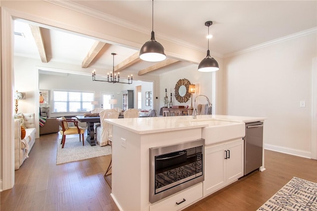 kitchen featuring appliances with stainless steel finishes, sink, decorative light fixtures, white cabinets, and an island with sink