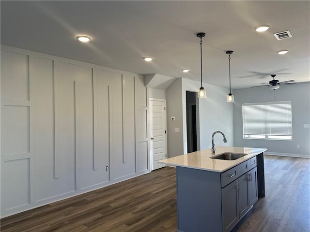 kitchen featuring dark hardwood / wood-style flooring, ceiling fan, a kitchen island with sink, sink, and pendant lighting