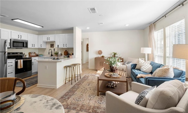 living room with baseboards, recessed lighting, light wood-style flooring, and visible vents
