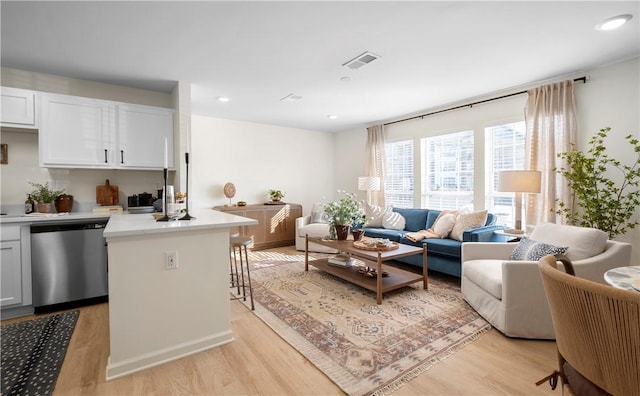 living room featuring recessed lighting, light wood-type flooring, and visible vents