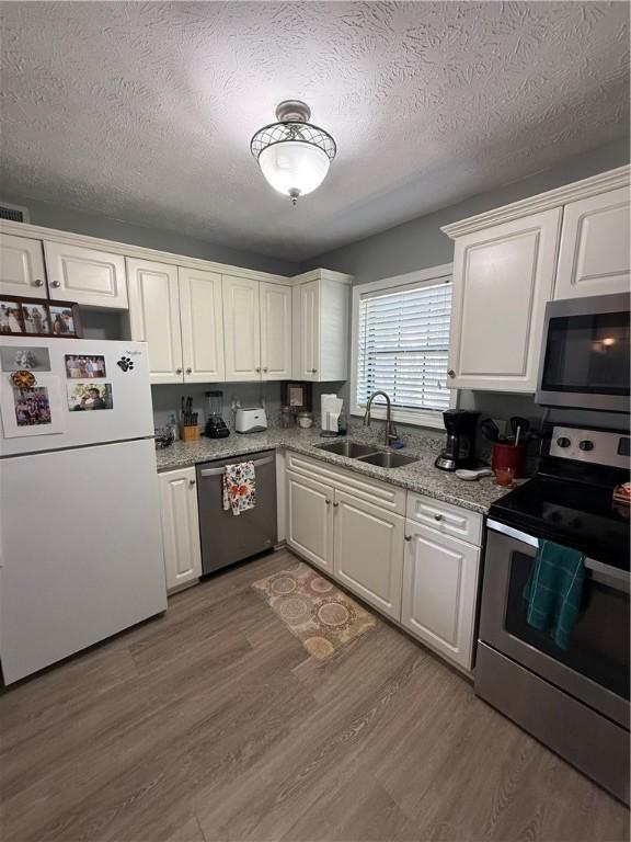 1825 Wire Rd Unit 15, Auburn, AL 36830 - kitchen with appliances with stainless steel finishes, a sink, a textured ceiling, white cabinetry, and wood finished floors