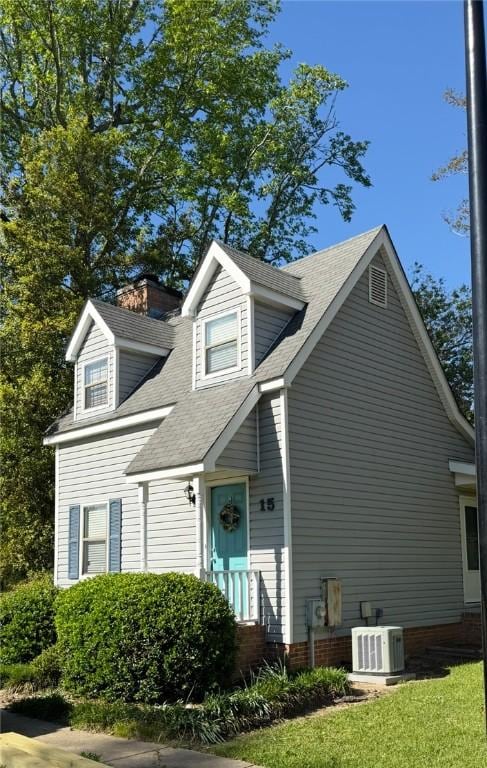 cape cod-style house featuring central AC unit and roof with shingles