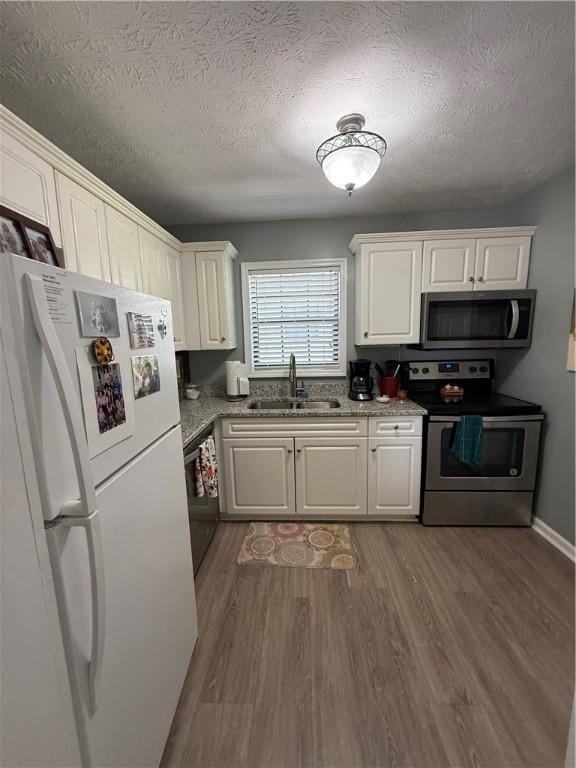 kitchen featuring a textured ceiling, appliances with stainless steel finishes, a sink, and dark wood finished floors