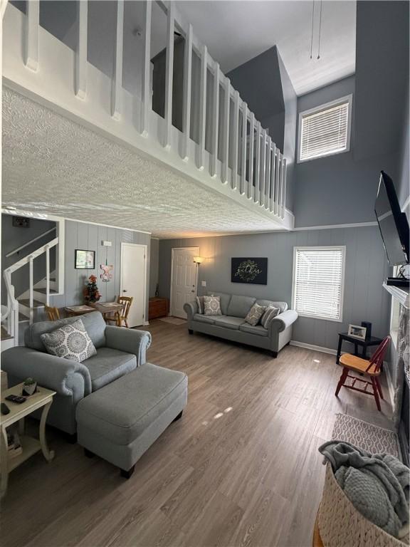 living room with wood finished floors, a decorative wall, a high ceiling, and a fireplace