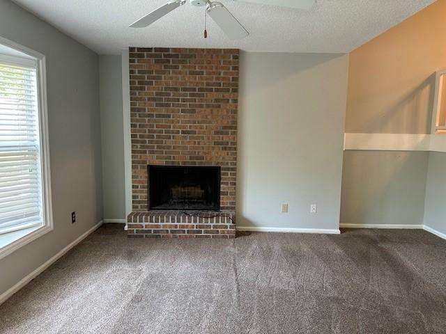 371 E Thach Ave Unit 4, Auburn, AL 36830 - unfurnished living room with ceiling fan, carpet flooring, a fireplace, a textured ceiling, and baseboards