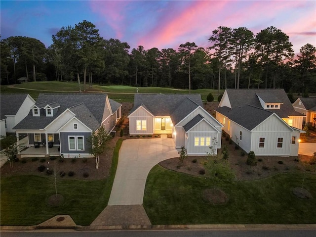 view of front facade featuring board and batten siding, a front yard, and concrete driveway
