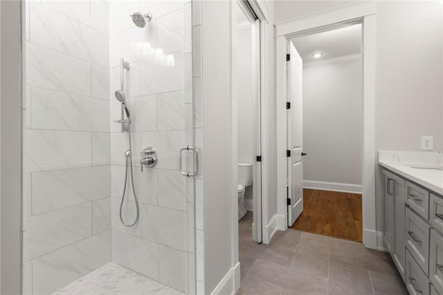 full bath featuring crown molding, vanity, toilet, baseboards, and tiled shower