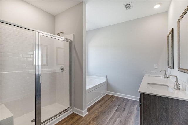 bathroom featuring a garden tub, a stall shower, a sink, and wood finished floors