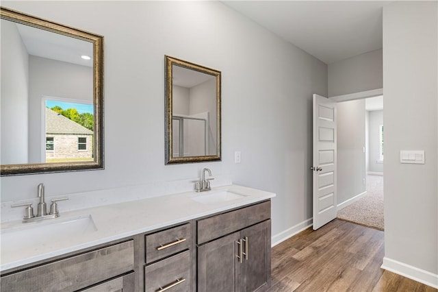 full bathroom with double vanity, baseboards, a sink, and wood finished floors