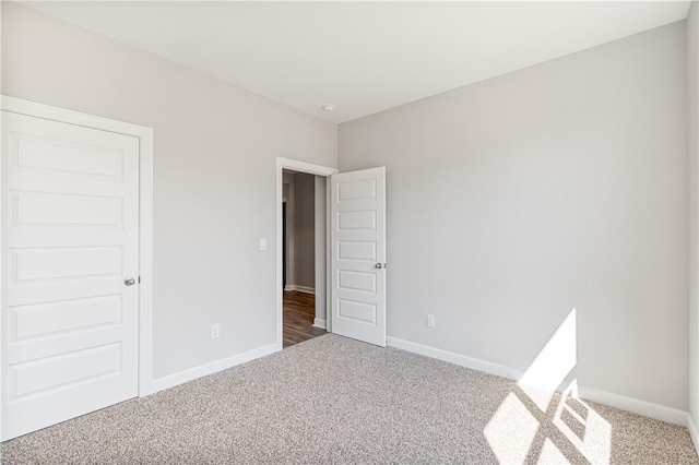 unfurnished room with carpet flooring and baseboards