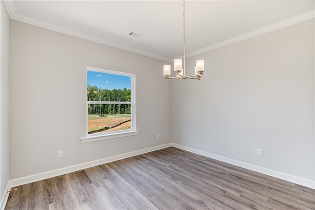 spare room featuring baseboards, crown molding, visible vents, and wood finished floors