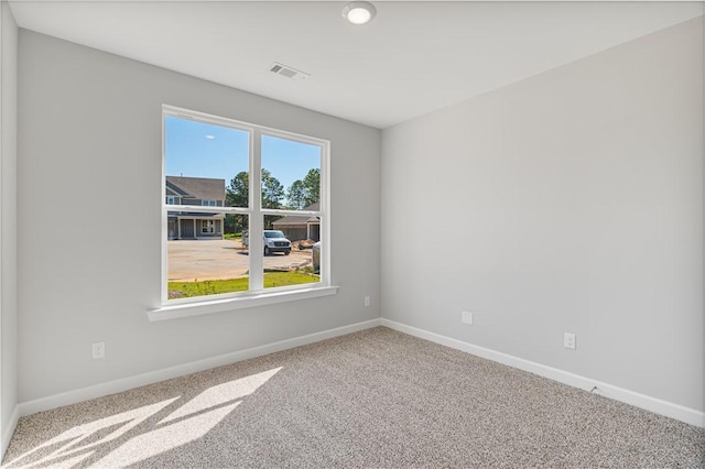 carpeted empty room featuring baseboards and visible vents