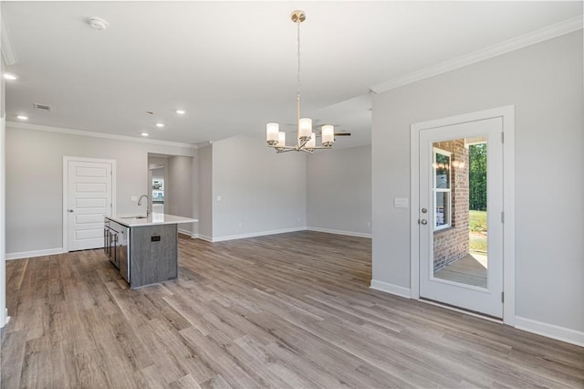 kitchen featuring crown molding, visible vents, a sink, wood finished floors, and baseboards