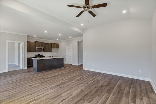 kitchen featuring open floor plan, appliances with stainless steel finishes, wood finished floors, and a kitchen island with sink