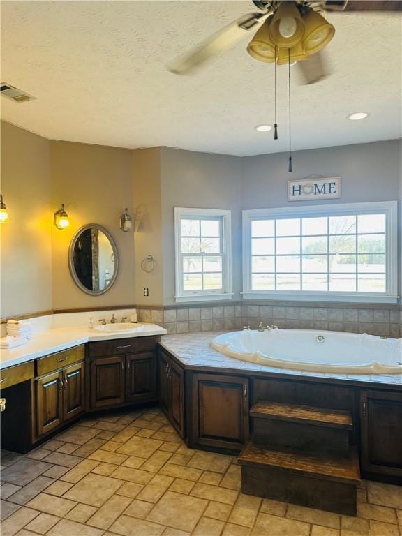 bathroom with plenty of natural light, ceiling fan, a tub, and vanity