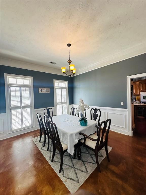 dining area with crown molding, plenty of natural light, and an inviting chandelier