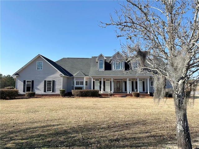 new england style home featuring covered porch and a front lawn