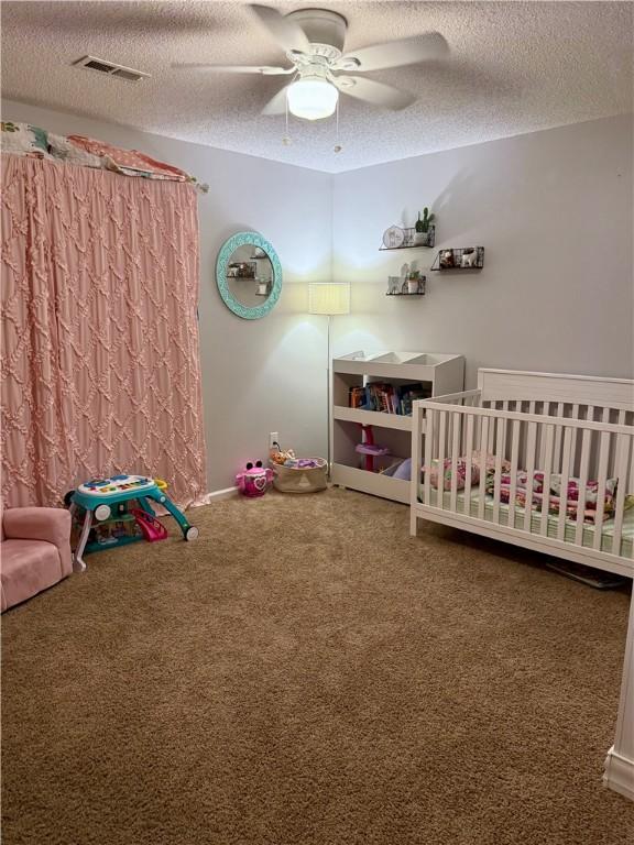 1202 Northgate Dr, Opelika, AL 36801 - carpeted bedroom with a textured ceiling, a crib, and ceiling fan