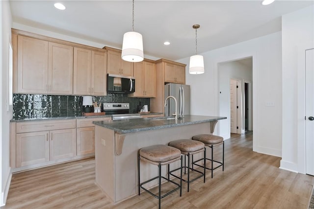 3228 Bradley Ln, Auburn, AL 36830 - kitchen featuring stainless steel appliances, tasteful backsplash, a kitchen breakfast bar, an island with sink, and light wood-style floors