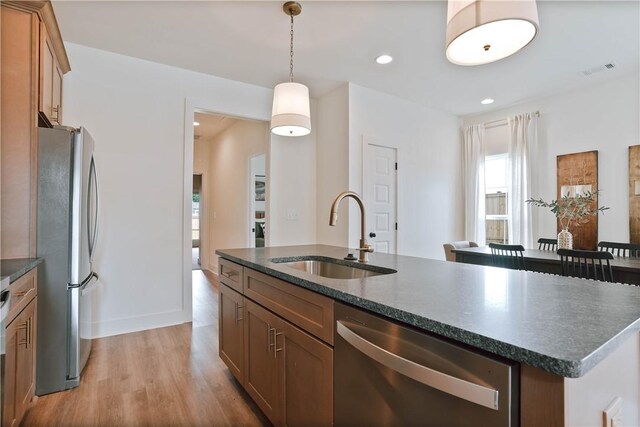 3228 Bradley Ln, Auburn, AL 36830 - kitchen with appliances with stainless steel finishes, a sink, light wood-type flooring, a kitchen island with sink, and brown cabinetry