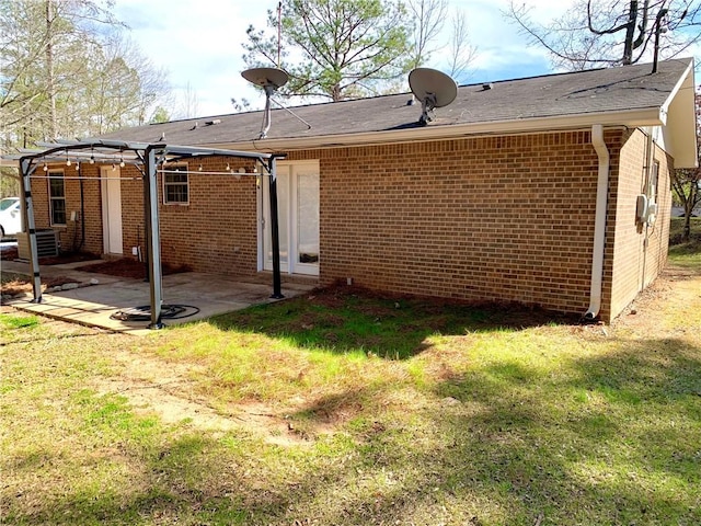 back of property featuring brick siding, a patio area, a pergola, and a yard