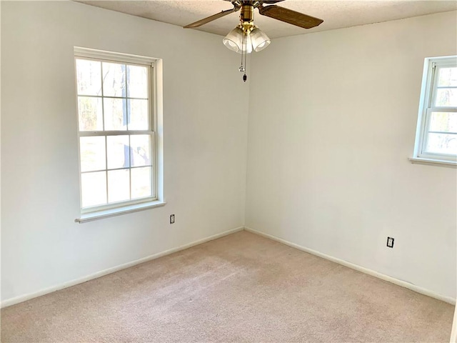 empty room with baseboards, light colored carpet, ceiling fan, and a textured ceiling