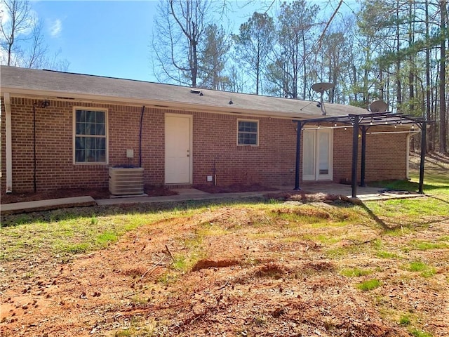 rear view of house featuring a pergola, a patio area, brick siding, and central AC